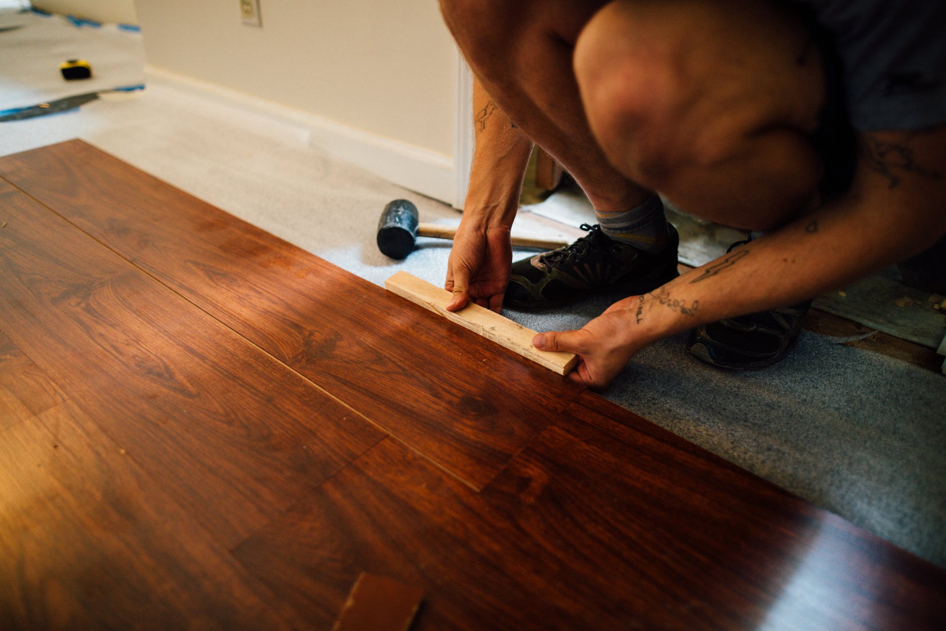 A man busy installing laminate flooring with a wood look to it